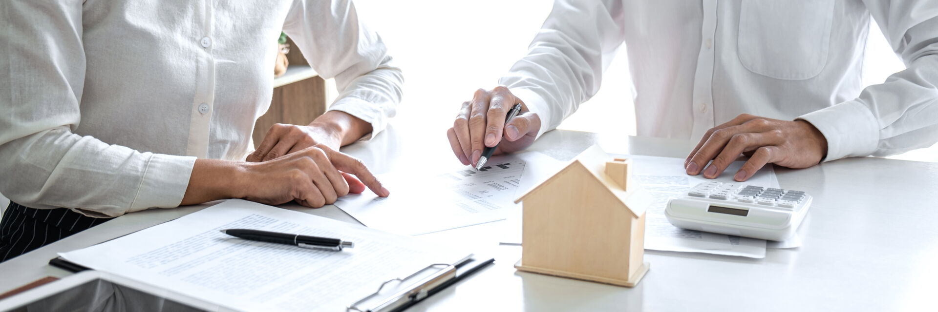 Zwei Personen unterzeichnen einen Immobilienvertrag neben einem Holzhausmodell in Bautzen. Immobilien Anders GmbH – Ihr Partner vor Ort.